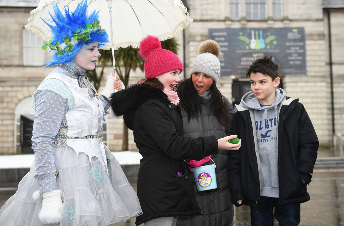 Karen Wallis with daughter Madelyn and son Charlie Wallis are wowed with magic tricks by magician Caolan McBride